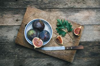 Figs and knife on chopping board and wooden table. Autumn season food photo