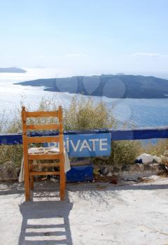 Royalty Free Photo of a Chair Overlooking the Caldera in Santorini