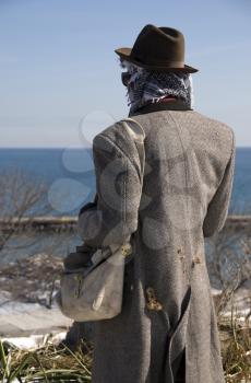 Royalty Free Photo of a Man in Tattered Clothes Looking at the Sea