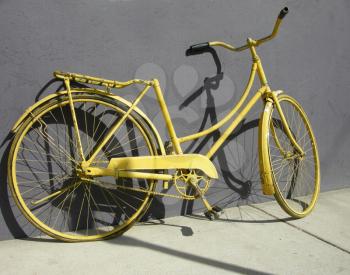 Royalty Free Photo of an Old Yellow Bike Leaning Against a Wall