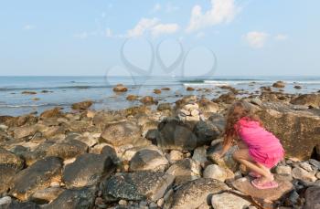 Royalty Free Photo of a Child Playing on Stones at the Beach