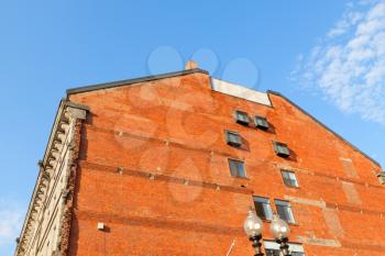 Red brick building wall with windows against the bright blue summer sky.