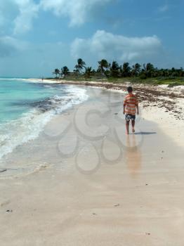 A boy walking on the caribbean beach.