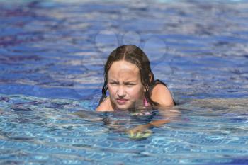 Girl is having fun in a pool at the tropical resort.