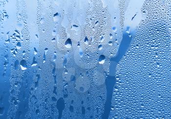 large and fine water drops on blue glass