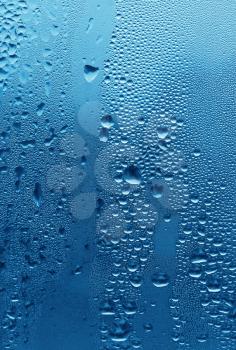 natural large and fine water drops on blue glass