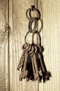 bunch of old rusty keys hanging on a wooden wall