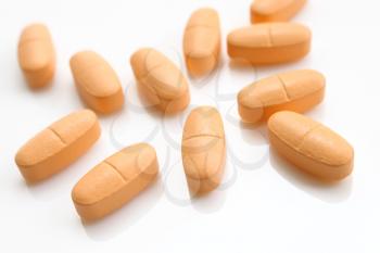 macro of orange pills isolated on white background