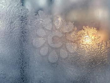 frosty natural pattern and sunlight on winter windowpane