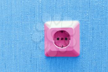 pink electric socket on blue wall, abstract background