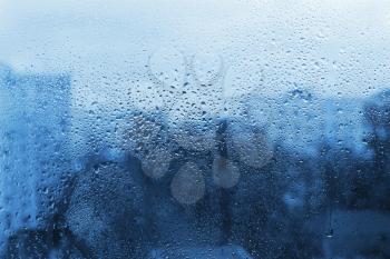 Water drops on window glass, blue natural background