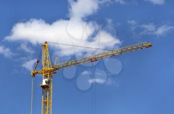 Construction crane against blue sky with white clouds