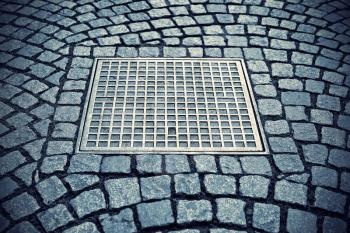 Paving stones background with metal manhole plate