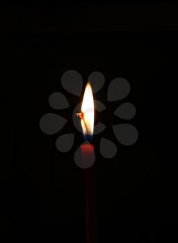 Closeup of bright burning candle in the dark