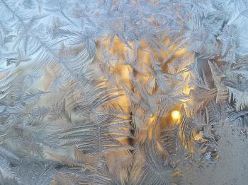 Texture of natural ice pattern and sunlight on winter glass