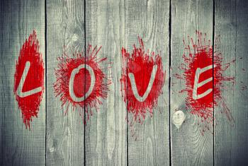 Bright red word Love on a grey wooden wall 