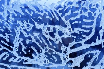 Bright blue abstract texture with soap foam pattern on glass