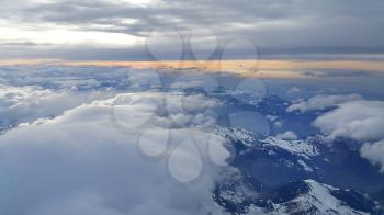 Beautiful panoramic top view on the evening Alps, covered with snow and clouds
