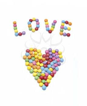 Word ''Love'' and abstract heart from bright colorful candy on white background