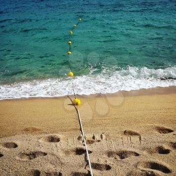 Rope with floats and footprints on the sea sand beach