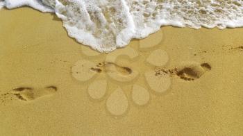 Nature background with sea foam and footprints in the sand