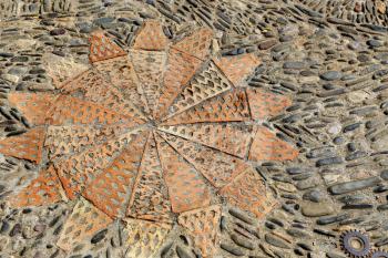 Patterned floor with sea pebbles red bricks and metal gears in the park Montjuic, Barcelona, Catalonia, Spain