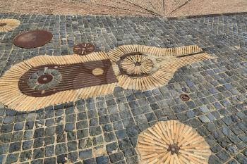 Unusual pavement with creative pattern from rusty metal details, ceramics, cobbles and red bricks. Park Montjuic, Barcelona, Catalonia, Spain.