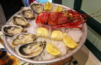 Large dish of fresh seafood, oysters with lobster with lemon and sauce on ice in a restaurant
