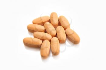 Heap of orange pills isolated on white background