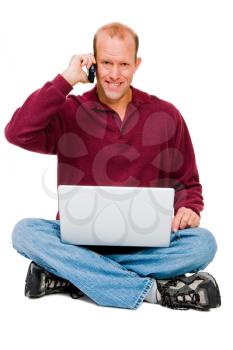 Royalty Free Photo of a Man Sitting Down Talking on his Cellular Phone and Holding a Laptop