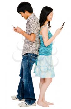 Royalty Free Photo of a Couple Standing Back to Back Texting on Their Cell Phones