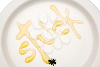 Royalty Free Photo of a the Word Stuck on a Plate Written with Honey with a Spider