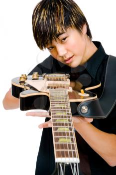 Close-up of a teenage boy playing a guitar and posing isolated over white