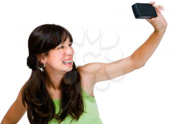 Happy teenage girl photographing herself with a camera isolated over white