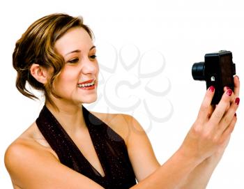 Gorgeous teenage girl photographing with a camera and smiling isolated over white