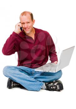 Smiling man using a laptop and a mobile isolated over white