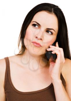 Thinking woman talking on a mobile phone isolated over white