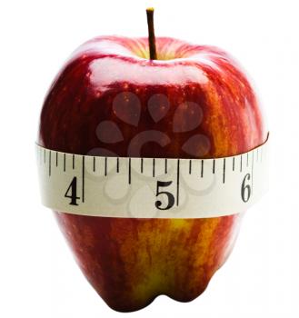 Close-up of a measuring tape wrapped around red apple isolated over white