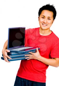 Close-up of a man holding a stack of laptops and smiling isolated over white