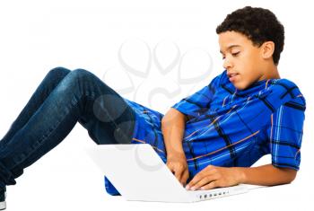 Teenage boy reclining on the floor and using a laptop isolated over white