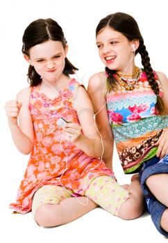 Smiling girls listening to MP3 player isolated over white