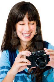 Teenager photographing with a camera and smiling isolated over white