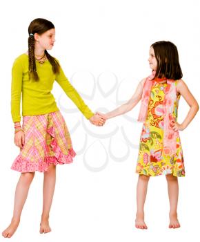 Two girls holding their hands and smiling isolated over white