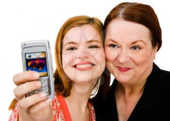 Smiling women photographing themself with a mobile phone isolated over white
