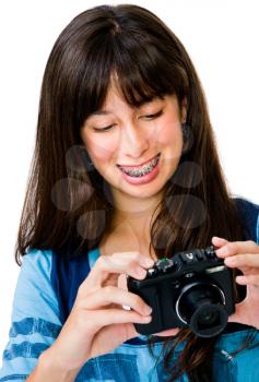 Close-up of a teenage girl photographing with a camera and smiling isolated over white
