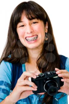 Portrait of a teenage girl photographing with a camera and smiling isolated over white
