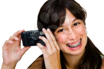 Teenager photographing with a camera and smiling isolated over white