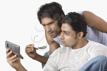 Two friends text messaging on a mobile phone