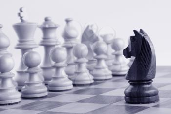 Black knight facing white chess pieces on a chess board
