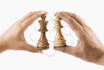Close-up of a man and woman's hands holding chess king and queen